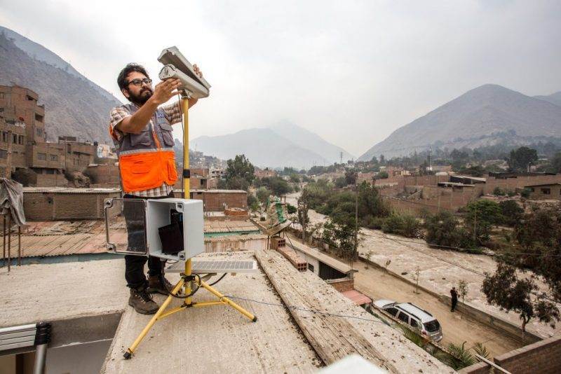 A man capturing photos on top of a roof, promoting The Climate Damages Tax.