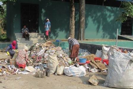 A group of urban slum dwellers standing next to a pile of garbage, advocating for change.
