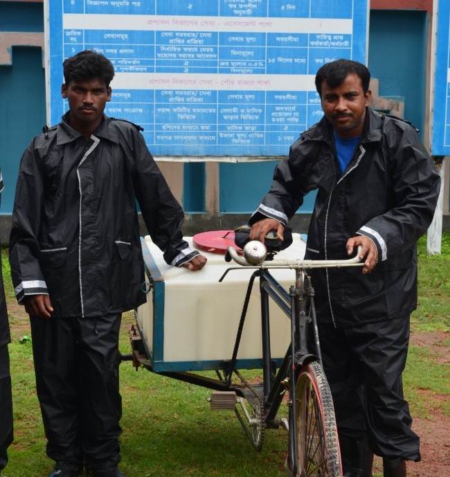 Three men displaying technical knowledge while standing next to a transport bicycle with a cart.