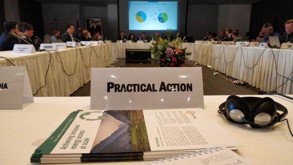 A group of people are sitting at a conference table discussing the climate investment funds after 10 years.