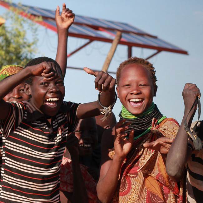 A group of children are in front of a transformative solar panel.
