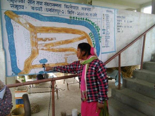 A woman pointing to a map on a wall, highlighting the commonality between flood resilience and Nepalese Thali.