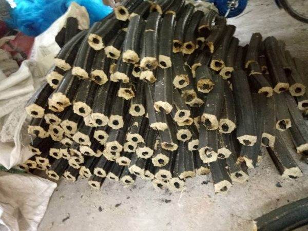 A pile of black rubber tubes, displaying innovations in briquette business for clean cooking energy, is located next to a bike.