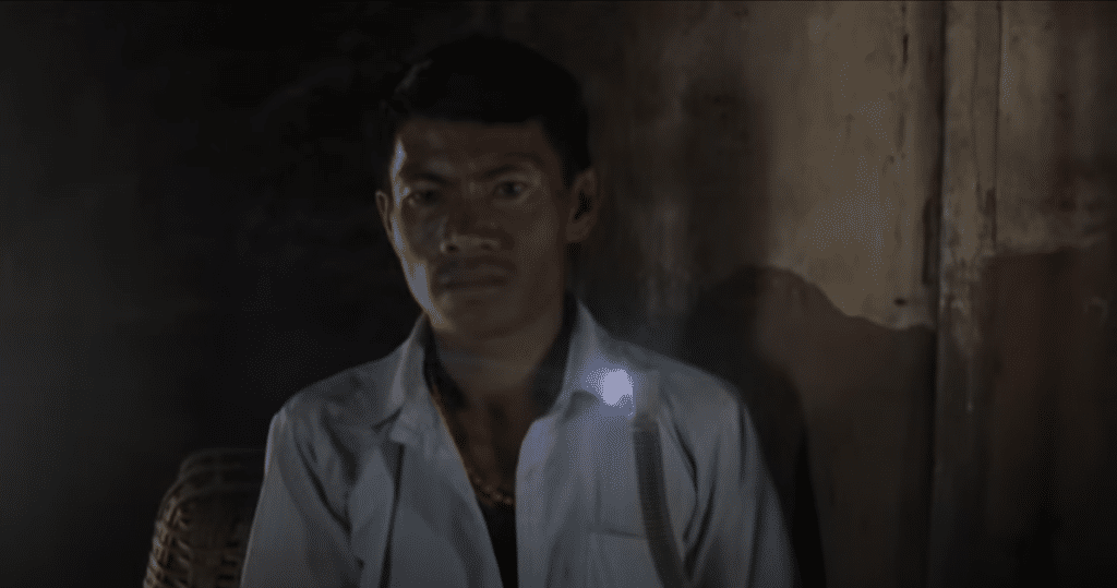 A man exploring renewable energy videos in a dark room with a flashlight.