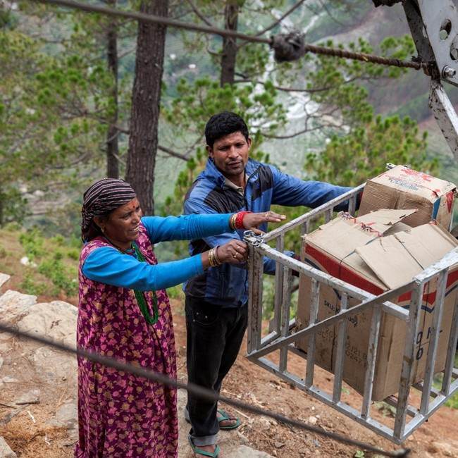 A man and a woman loading boxes on a crane, connecting Nepalese farmers.