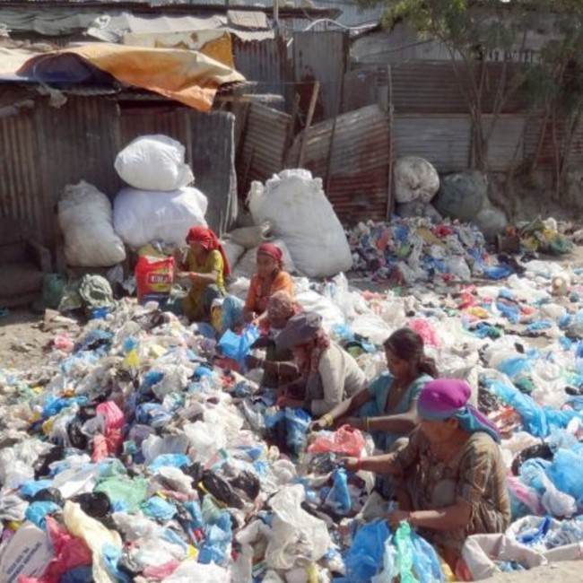 A group of individuals in Nepal seeking to escape a rubbish life gathered around a pile of garbage.