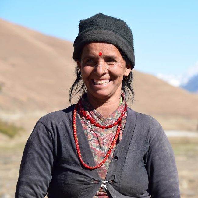 Starting small, a woman smiling in front of a mountain in Karnali.