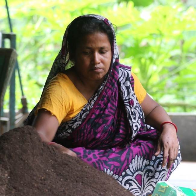 A woman in a sari empowering waste management in challenging conditions.