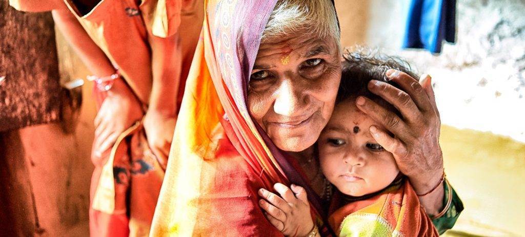 An old woman is lovingly holding a child in her arms