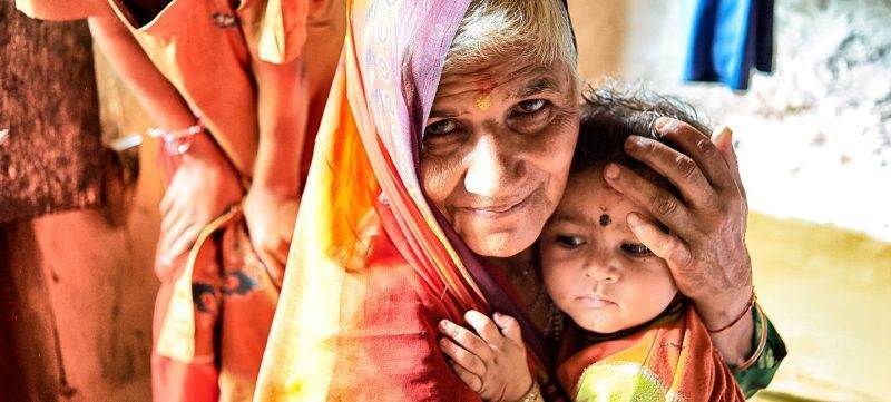An old woman is lovingly holding a child in her arms, urging others to donate in memory.