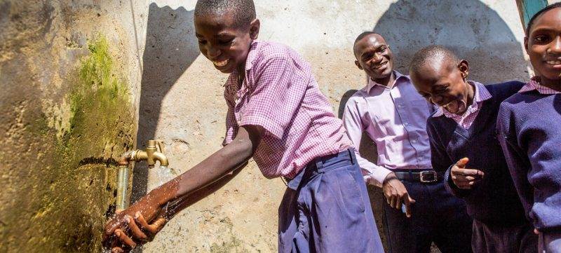 Children beside a water tap engaging in More ways to give.