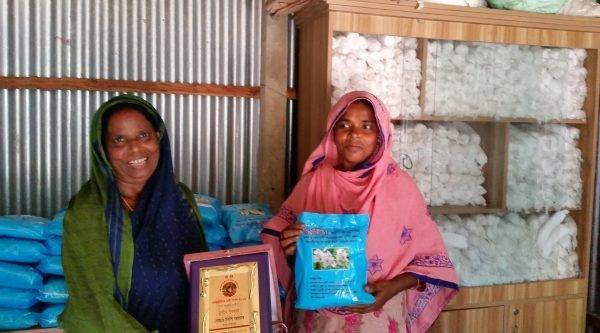 Two women advocating action on Menstrual Hygiene Day 2019, standing in front of a room full of clothes.