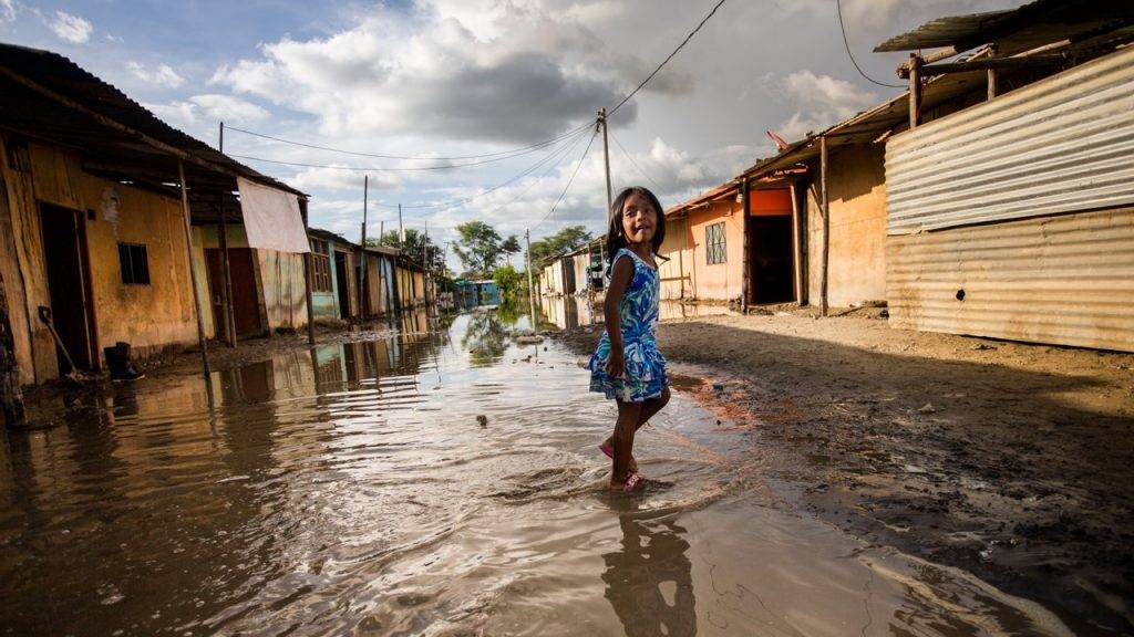 A girl navigates through a flooded street in a slum during a flood alert.