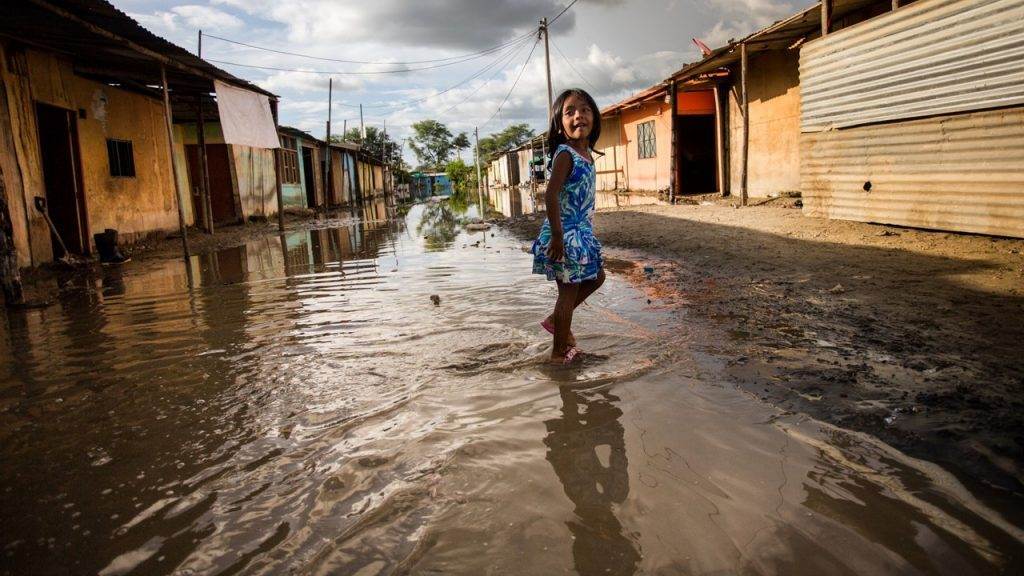 A girl braving a flooded street amidst an upd8 in a flood alert.