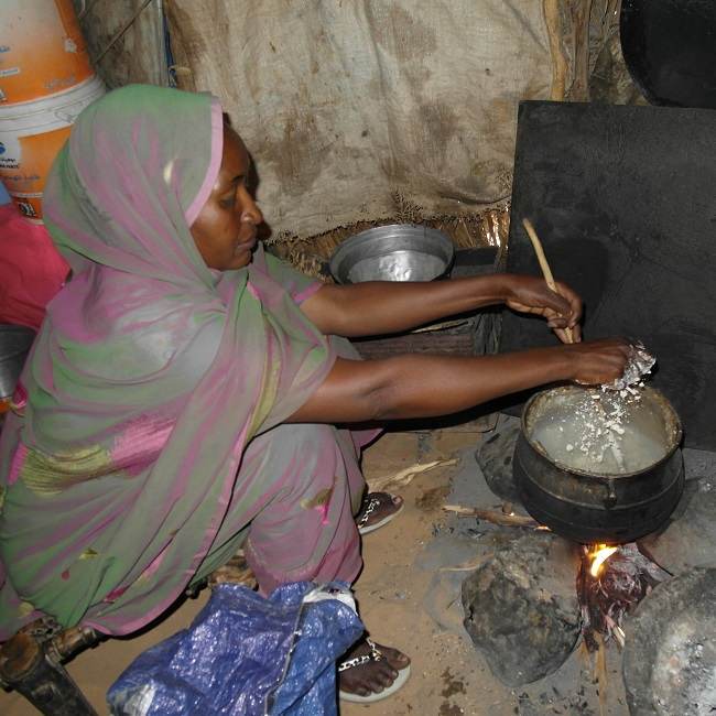 A woman clearing the air in a hut in Darfur.