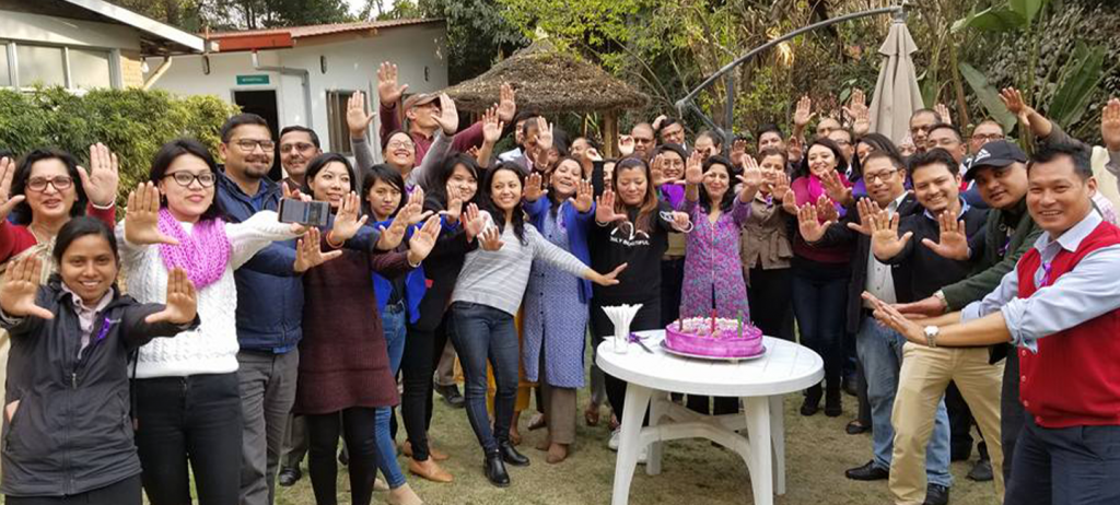 A group of people posing in front of a cake.