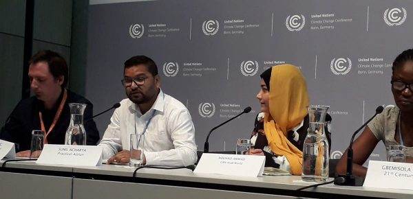 A group of people discussing climate issues at a table in front of microphones.