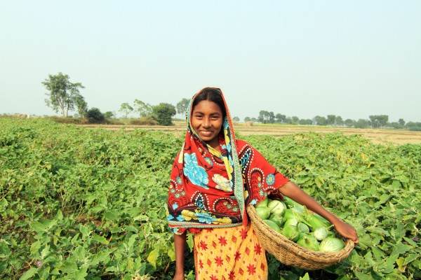 A girl holding a basket of vegetables in a field explores recycling human waste into a useful resource.