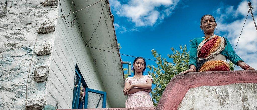 Two women standing on the steps of a house, reflecting the Poor People's Energy Outlook (PPEO).