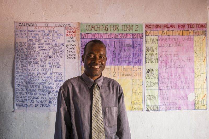 A man in a tie standing in front of a wall full of posters challenges the notion that water and electricity don't mix.