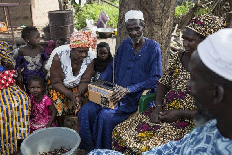 A group of people using ICT to listen to agricultural programs on the radio.