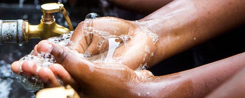 A person using a faucet to cleanse their feet for hygienic purposes.