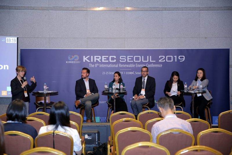 A group of people sitting in front of a stage at a conference discussing the global energy transition towards renewables.