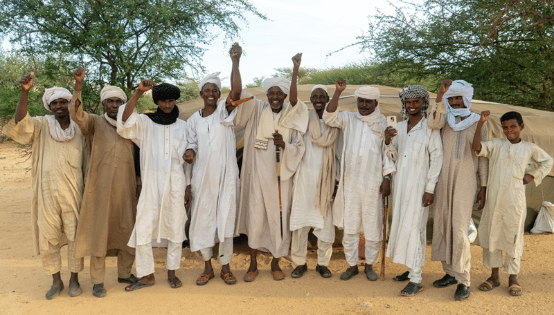 A group of men raising their hands in a fragile environment, working together to build peace and dams.