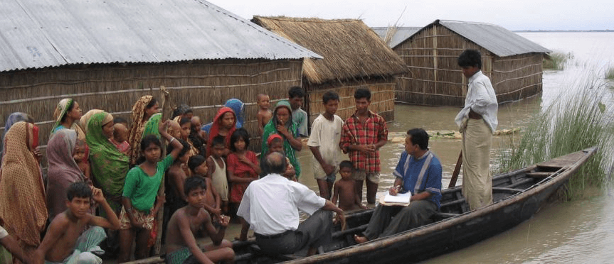 Climate change images: A group of people on a boat navigating through a flooded area.