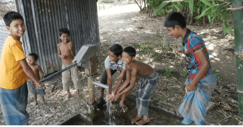 A group of children are washing their hands at a water well in a Pump it up! video.
