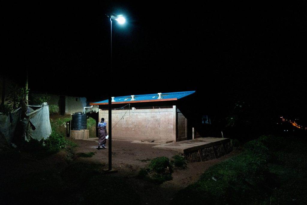 A small hut illuminated at night in a refugee camp, symbolizing the transformation into a city.