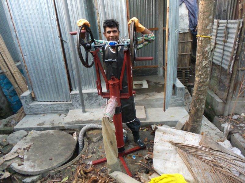 A man promoting health in the slums by standing next to a machine.