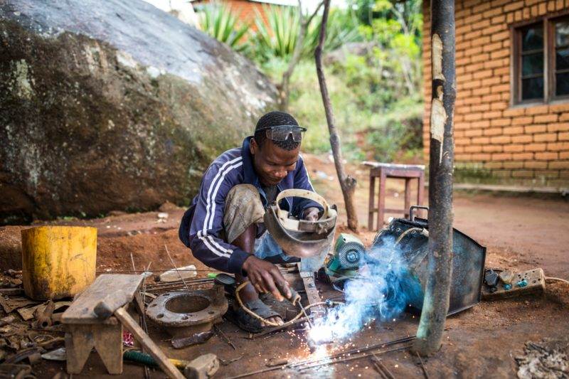 A man meeting the energy needs of the 'last mile' by operating a welding machine in a village.
