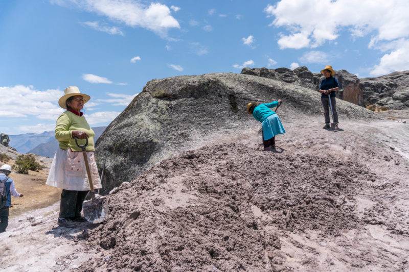 A group of indigenous people demonstrating their ancestral water management knowledge on top of a large rock.