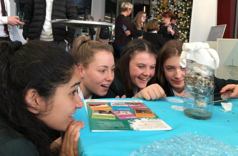 A group of girls are looking at a book on a table.