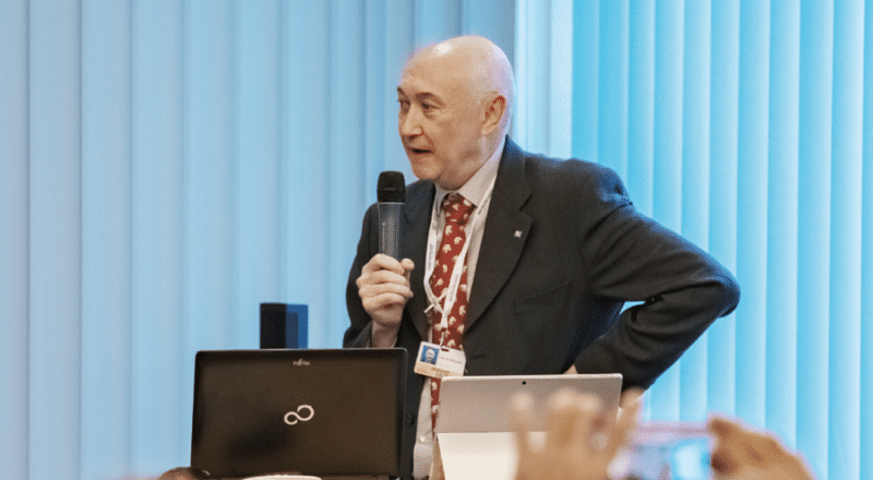 A man in a suit speaking into a microphone.