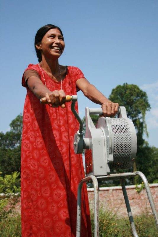 A woman smiling while riding a disaster risk reduction machine.