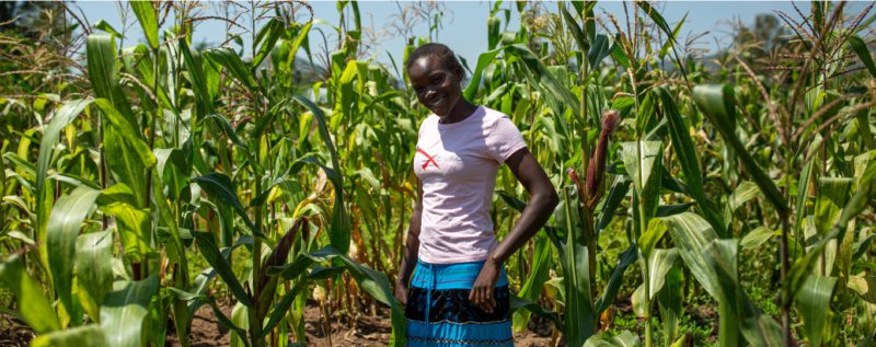 Farmer in Kenya smiling with her crops