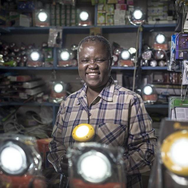 A woman standing in front of a store full of lights.