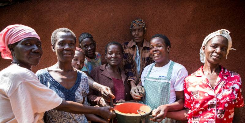 A group of women harnessing energy that transforms by holding a bucket of food.