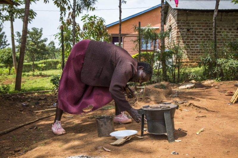 A rural woman is using a smart stove in Kenya to cook, promoting healthier homes.