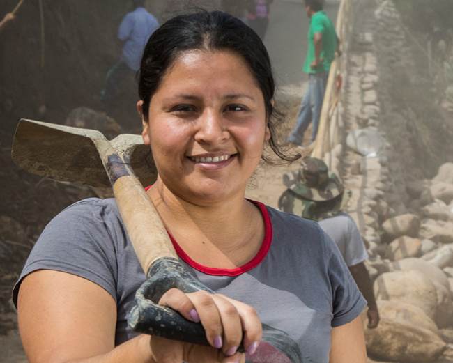 A woman wielding a shovel powerfully influences a diverse group of people.