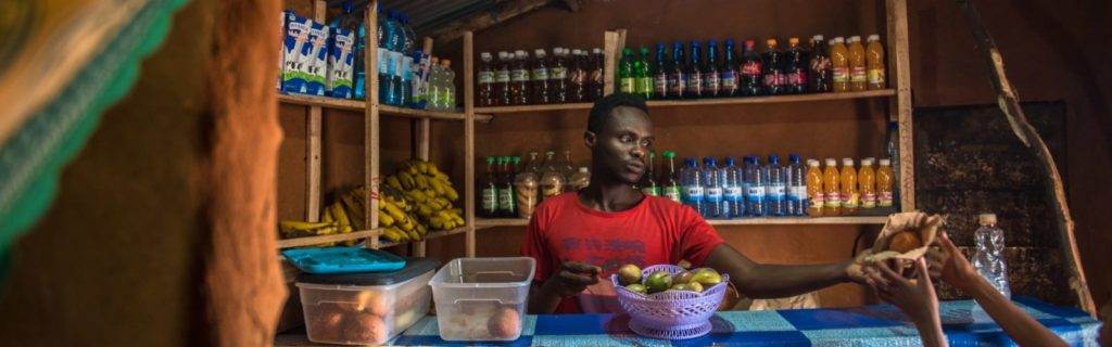 A man is standing in front of a small shop