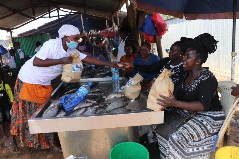 A group of people selling fish at an outdoor market, building futures.