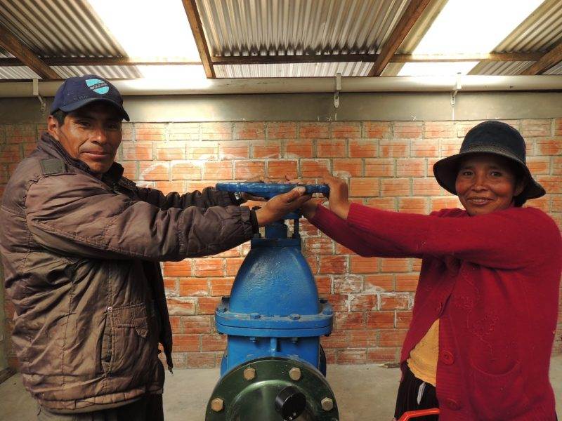 A man and a woman standing next to a blue water hydrant, symbolizing their efforts in building futures.