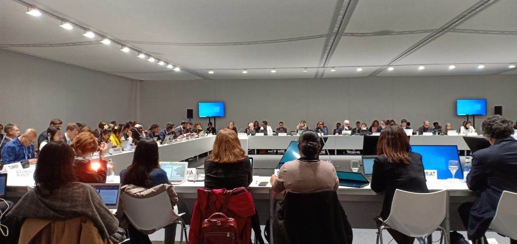 A group of people sitting at a table in a conference room at COP26.