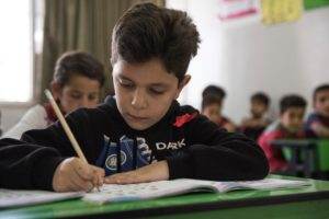 A boy is experiencing the transformative power of learning at a desk in a classroom.