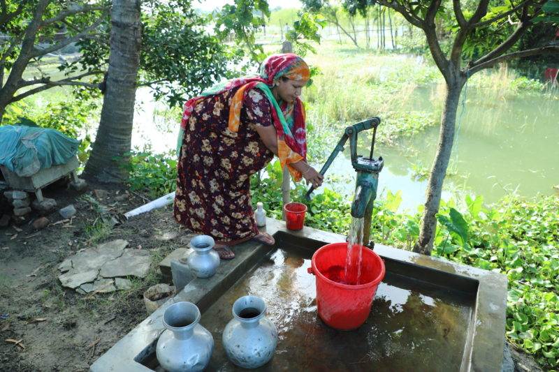A woman is adapting to climate change by filling water from a well.