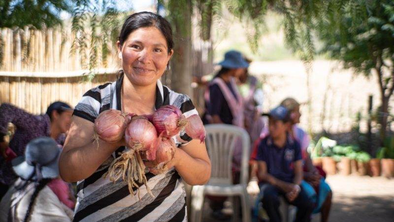A woman displaying a bunch of onions as she receives the new award for contribution to ending hunger in Bolivia.