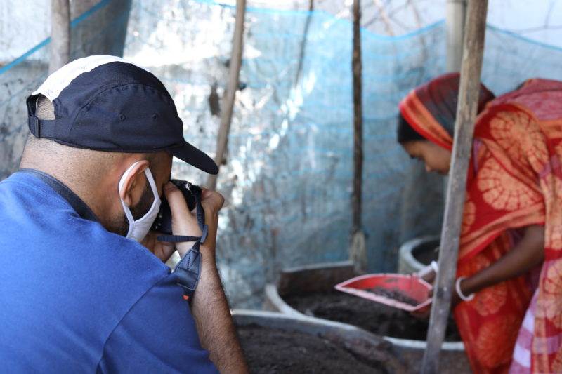A man captures a photograph of a woman in a red sari, showcasing Practical Action's involvement in the national Climate Change appeal.